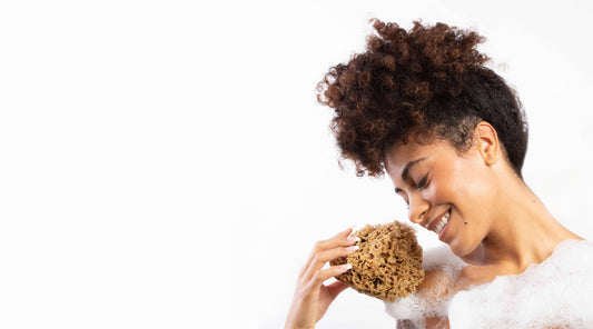 Model holding ocean sea sponge with upper body showing but covered with lather.