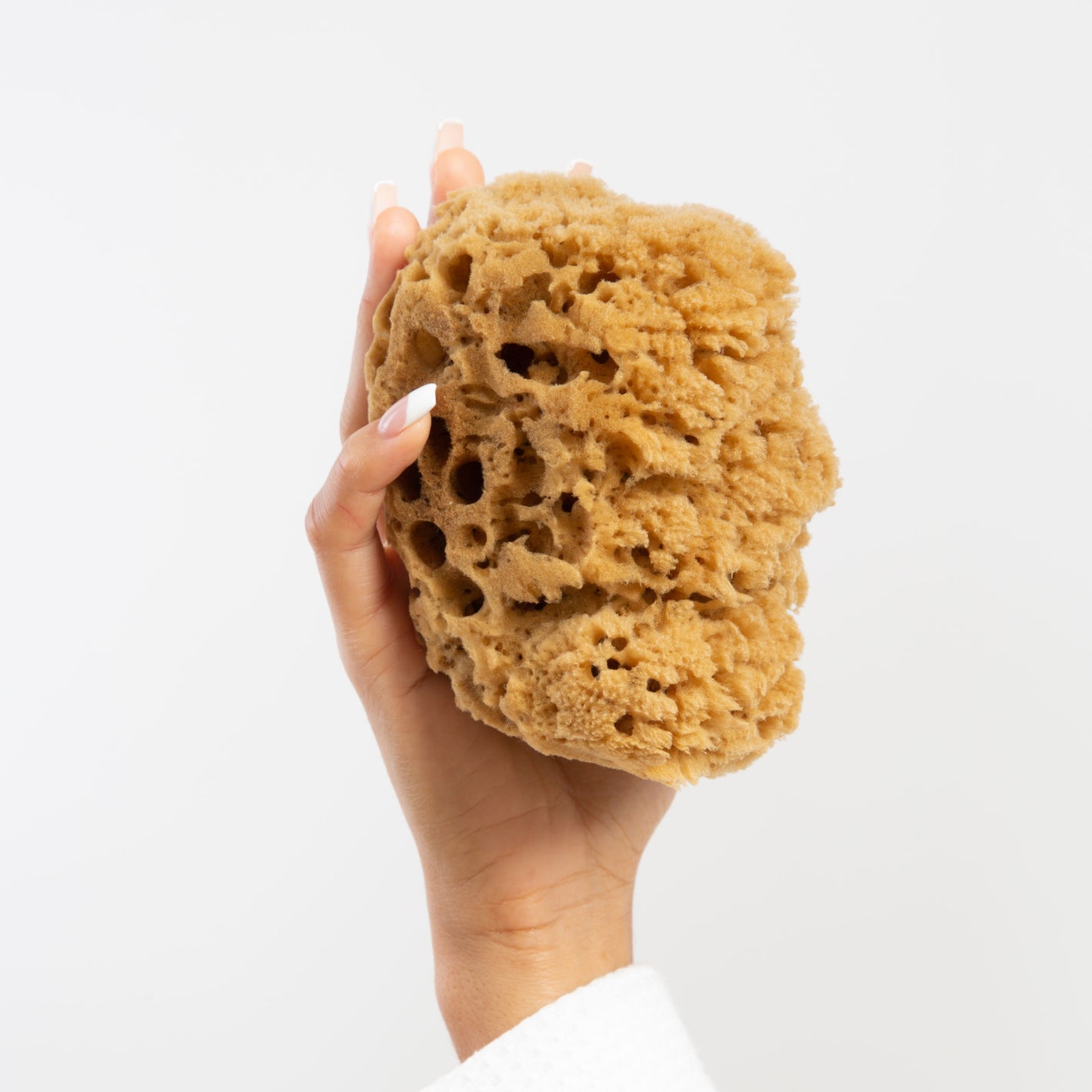 Natural Naroa massage shower sponge held in hand light brown colour with hair like fibres