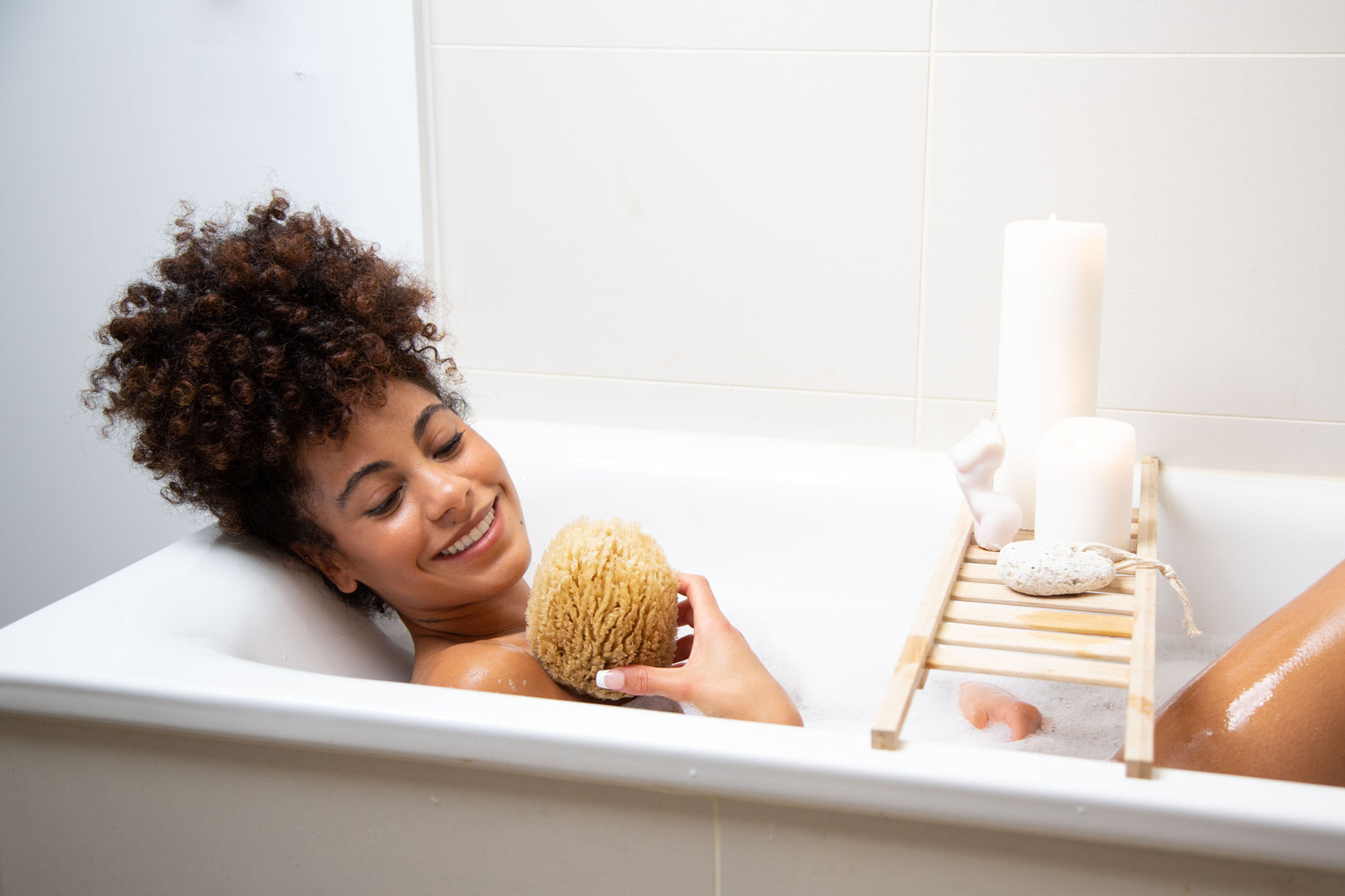Woman in bath holding naroa sponge
